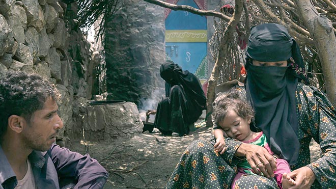 بشرى علي صغير صربان تحمل ابنتها رينا خارج منزلها مع زوجها محمد